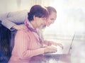 Younger woman helping an elderly person using laptop computer for internet search. Royalty Free Stock Photo