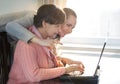 Younger woman helping an elderly person using laptop computer for internet search. Young and pension age generations working Royalty Free Stock Photo