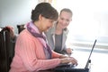 Younger woman helping an elderly person using laptop Royalty Free Stock Photo