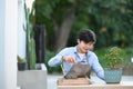 A youngman planting a bonsai tree into pot in garden.