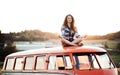 A young girl on a roadtrip through countryside, sitting on the roof of minivan doing yoga. Royalty Free Stock Photo