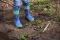 Youngster is standing in a mud with his rainboots.