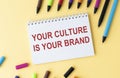 Your culture is your brand - handwriting on a notepad on yellow table with