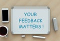 Your Feedback Matters, message on whiteboard, smart phone and coffee on table Royalty Free Stock Photo