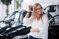 Your keys. Young manager in the auto shop stands against perfectly polished black car