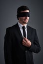 Is your lack of vision limiting you. Studio shot of a young businessman wearing a blindfold against a gray background.