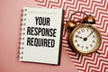 Your Response Required text written on notepad with alarm clock Royalty Free Stock Photo