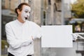 Your text here. Actor mime holding empty white letter. Colorful portrait with gray background. April fools day