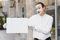 Your text here. Actor mime holding empty white letter. Colorful portrait with gray background. April fools day