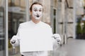 Your text here. Actor mime holding empty white letter. Colorful portrait with gray background. April fools day