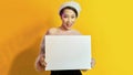 Your text here. Pretty young excited woman holding empty blank board. Colorful studio portrait with yellow background Royalty Free Stock Photo