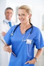 Youre in capable hands. Portrait of a female doctor in scrubs with a colleague standing in a the background. Royalty Free Stock Photo