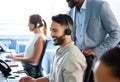 Youre doing a good job. a handsome young call centre agent sitting and using his computer while his manager watches. Royalty Free Stock Photo