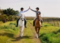 Youre doing great. Full length shot of two young woman high fiving while riding their horses on the ranch.