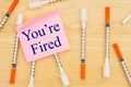 Youre Fired message with vaccine needle on desk with a sticky note