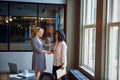 Youre going to fit in well here. two smiling businesswomen shaking hands in an office. Royalty Free Stock Photo