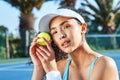 Youre looking at the winning ball. an attractive young woman standing and holding a tennis ball while looking