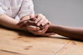 Youre never alone. a two people holding hands in comfort on a table.