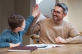 Youre such a smart kid. a father high fiving his son while they complete his homework.