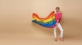 Youth asian transgender LGBT with Rainbow flag isolated over nude color background. Man with a gay pride flag concept