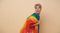 Youth asian transgender LGBT with Rainbow flag on shoulder isolated over nude color background. Man with a gay pride flag concept