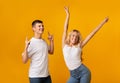 Joyful millennial guy and girl dancing in studio over yellow background