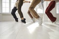 Group of hip hop dancers who together perform stand on toes during rehearsal in dance studio.