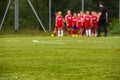 Youth Football Team with Coach on Pitch; Blurred Soccer Background.