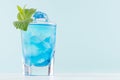 Youth fresh alcohol blue Hawaii cocktail with liquor curacao, ice cube, green mint in shot glass on elegant pastel mint background Royalty Free Stock Photo