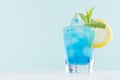 Youth fresh alcohol blue Hawaii cocktail with liquor curacao, ice cube, salt rim, lemon, mint in shot glass on elegant pastel mint