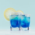 Youth fresh alcohol blue Hawaii cocktail with liquor curacao, ice cube, salt rim, lemon slice on elegant pastel mint background.