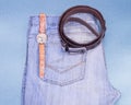 Youth jeans, wrist watches, leather strap on a blue background