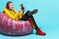 Youth Lifestyle Concepts. Winsome Teenager Girl in Hooded Jacket With Gamepad Joystick While Using Cellphone For Gaming in Cushion Royalty Free Stock Photo