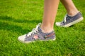 Youth sneakers on girl legs on grass