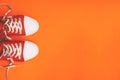 Youth sneakers on an orange background with copy space. Red sneakers with loose laces. Minimal style. Top view, flat lay Royalty Free Stock Photo
