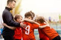 Youth Sports Team. Kids with junior soccer coach huddling in a circle