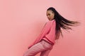 Studio shot of young excited girl with afro hairdo in casual style outfit having fun isolated on pink background Royalty Free Stock Photo