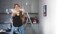 Youthful caucasian independent long-long haired woman in her own maker space holding a hammer and showing thumbs up to