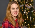 Youthful forty-seven yearold redheaded woman posing in front of her Christmas tree in her home in Saint Louis, Missouri.