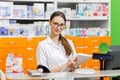 A youthful pleasant dark-haired girl with glasses,dressed in a medical overall,writes notes in a notebook at the cash