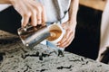 A youthful slim kind blonde girl,dressed in casual outfit,skillfully adds milk to coffee in a modern coffee shop.