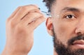 Youthfulness in every drop. Studio portrait of a handsome young man applying face serum against a blue background.