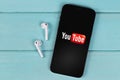 YouTube mobile logo app on screen smartphone iPhone with AirPods on a colored background Royalty Free Stock Photo