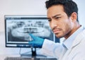 Youve been found out. a young dentist pointing to an xray of a patients teeth.