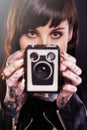 Youve been framed. Studio shot of a young tattooed woman holding a vintage camera.