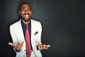 Youve got be kidding me, right. Portrait of a young businessman shrugging against a dark background. Royalty Free Stock Photo