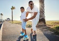 Youve got the hang of it. a father helping his son skateboard along the promenade. Royalty Free Stock Photo