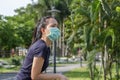 The ypung woman in medical protective mask relaxing in the park. campaign to use protective mask from COVID19