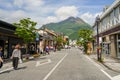 Main road from train station filled with people, streetscape and local shops direct to fresh green Yufudake mountain peak and blue Royalty Free Stock Photo