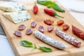 Yummy assortment of sausages, hot peppers, and blue cheese on a wooden board